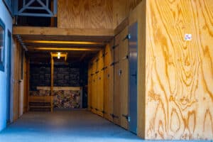 Passage intérieur en bois avec casiers, décor mural Coffee Shop, X-Men, et panneau "interdit de fumer". Porte numéro 61 visible.