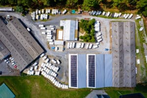 Complexe industriel avec vastes entrepôts, centaines de caravanes et bateaux stockés en extérieur. Grands panneaux solaires sur un toit.